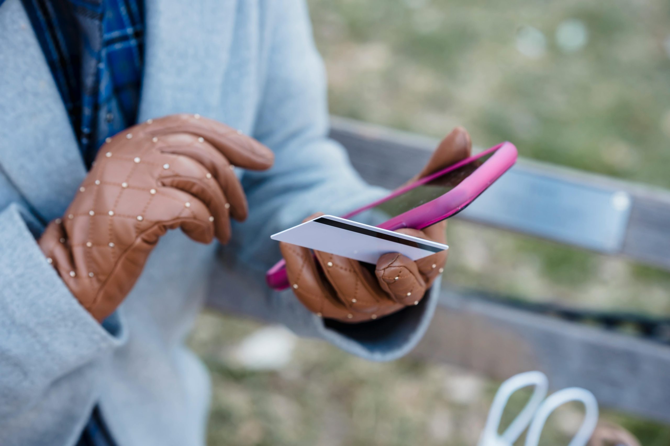 Woman wearing gloves holding smart phone and credit card