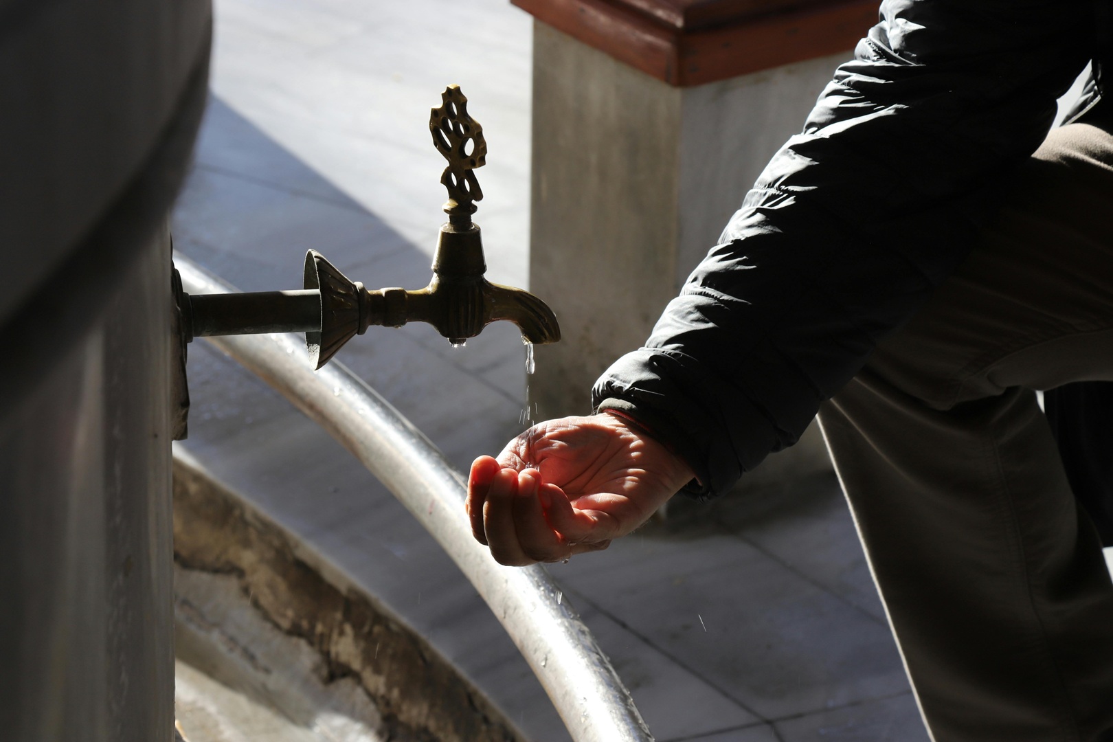 Hand catching water from a slow-dripping faucet, symbolizing small business profit leaks