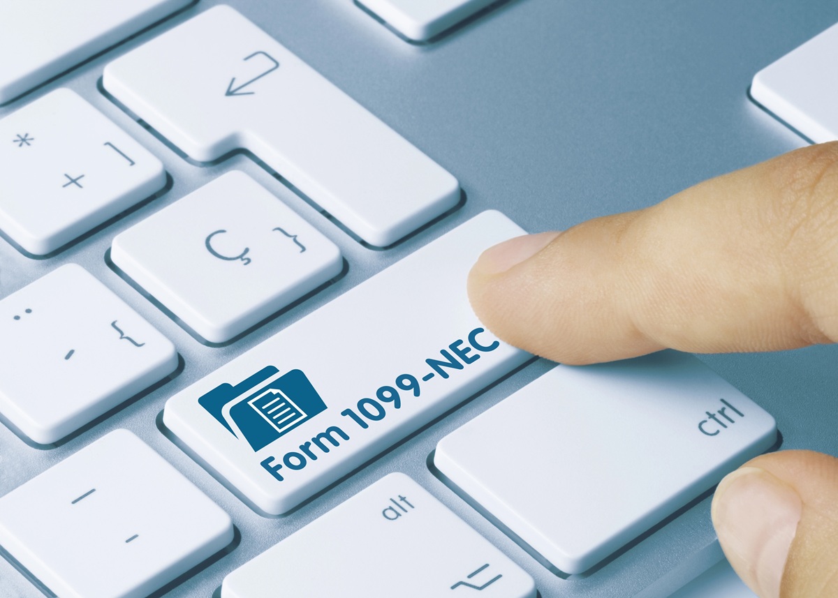 Finger pressing blue keyboard key labeled “Form 1099-NEC” — concept for year-end 1099 prep and tax filing.