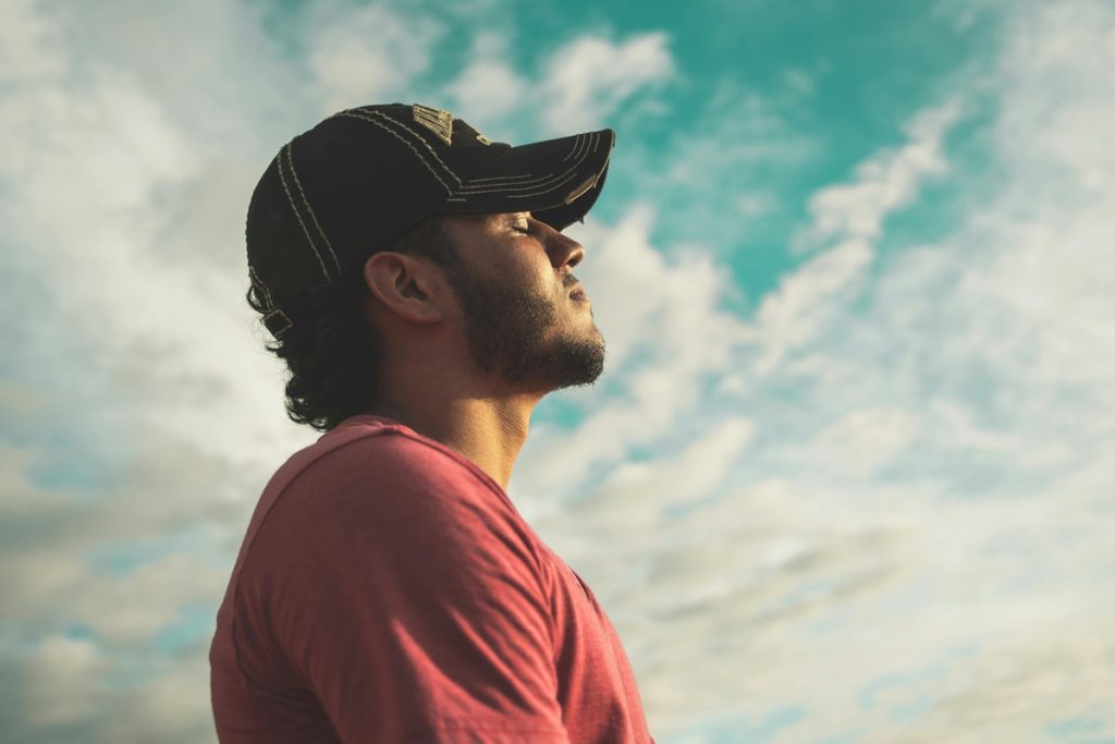 Person standing in quiet reflection under an open sky, symbolizing a shift in money mindset