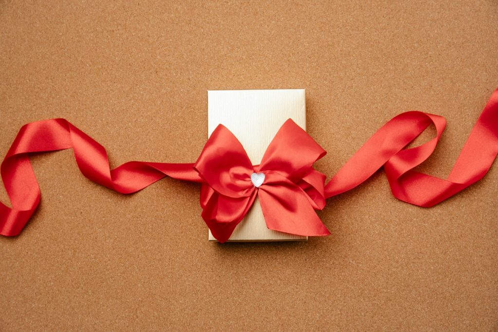 gold business gift box with a red ribbon on a cork background illustrates keep it simple